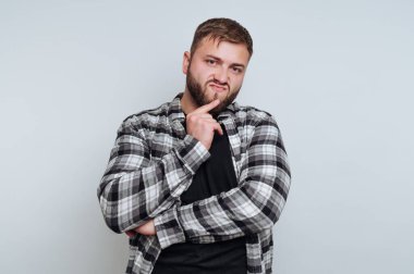 Ekose gömlekli adam düşünceli bir ifade takınıyor.