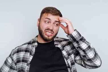 Ekose gömlekli adam kafası karışmış ve hayal kırıklığına uğramış görünüyor.