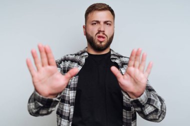 Ekose gömlekli bir adam iki eliyle jest yapıyor..