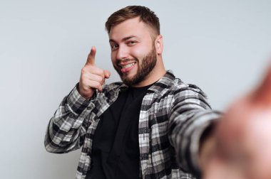 Ekose gömlekli gülümseyen adam kameraya neşeli bir ifadeyle bakıyor..