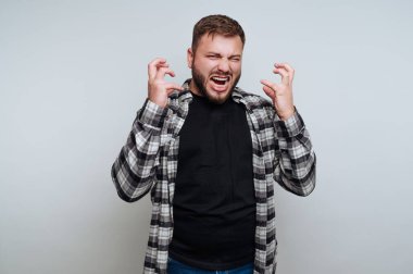 Öfkesini dışa vuran, ekose gömlek ve siyah tişört giyen tarafsız bir adam.