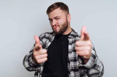 Ekose gömlekli bir adam, neşeli bir ifadeyle parmak tabancası hareketi yapıyor..