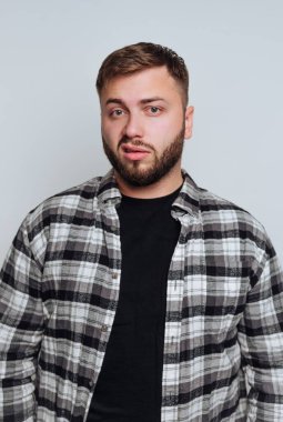 Sakallı, ekose tişörtlü ve siyah tişörtlü bir adam..