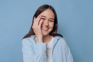 Mavi çizgili tişörtlü gülümseyen kadın mavi arka planda.