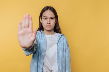 Genç bir kadın sarı arka plana karşı bir jest yapıyor..