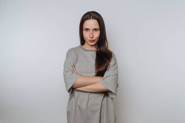 Uzun saçlı, kollarını kavuşturan, gri gömlekli bir kadın..