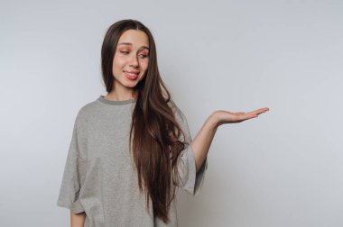 Gri tişörtlü genç bir kadın açık elle el hareketi yapıyor.