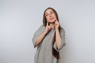 Gri gömlekli bir kadın arka planda şakacı bir şekilde poz veriyor..