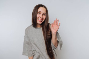 Gülümseyen kadın beyaz arka planda gri gömleğini sallıyor..