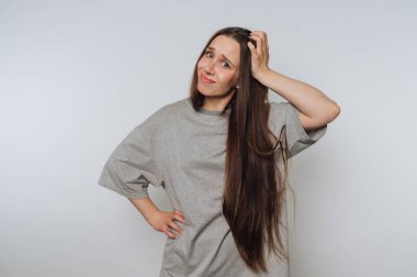 Kafasını kaşıyan uzun saçlı, kafası karışmış bir kadın..