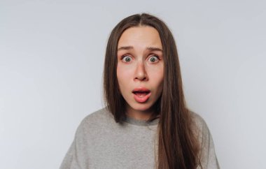 Uzun saçlı, gri gömlekli, sade bir geçmişi olan, şaşırmış bir kadın..