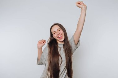 Uzun saçlı genç kadın sevinçle kutluyor, kolları havada..