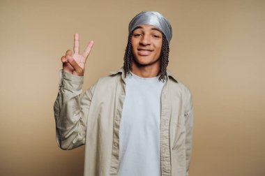 Duraglı genç bir adam barış işareti yapıyor.