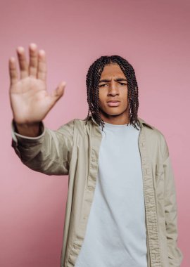 Örgülü genç adam pembe arka plana karşı jest yapıyor..
