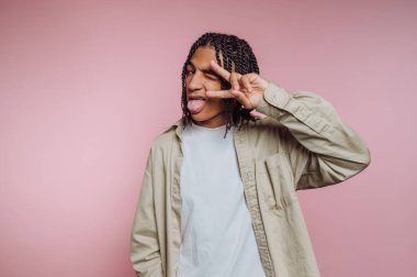 Dilini çıkarmış, barış işareti yapmış, şakacı bir jest yapan kişi..