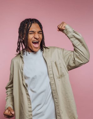 Pembe arka planda yumruk tokuşturarak kutlama yapan kişi.