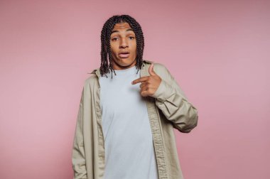 Pembe arka planda kendini gösteren örgülü saçlı genç bir adam..