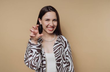 Kadın, bej arka plandaki pençe hareketini şakayla taklit ediyor..