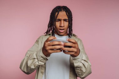 Saçları örgülü genç bir adam seyyar bir oyun oynuyor, şaşırmış görünüyor..