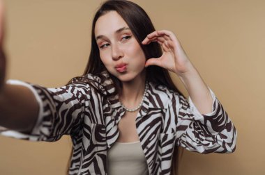 Genç bir kadın neşeli bir ifadeyle selfie çekiyor..