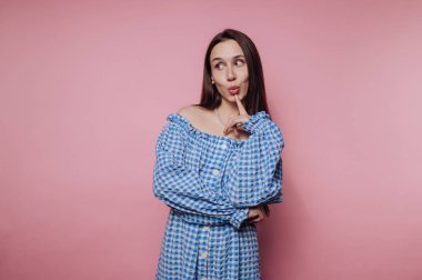 Mavi elbiseli kadın pembe arka planda poz veriyor..