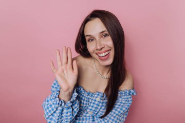 Mavi kareli gülümseyen kadın pembe arka planda sallanıyor.