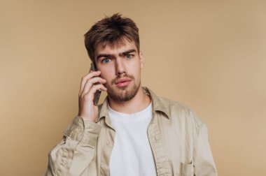 Akıllı telefondan konuşan, şaşırmış bir suratı olan genç adam..