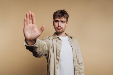 Ciddi bir ifadeyle genç bir adam dur jestinde el ele tutuşuyor..