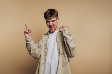 Genç adam bej arka planda heyecanla kutluyor..