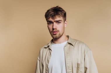 Bej bir geçmişe karşı şaşırmış bir ifadesi olan genç adam..