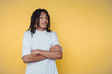 Sarı arka planda beyaz tişörtlü, rastalı genç adam.