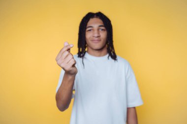 Sarı arka planda parmakları olan biri kalp hareketi yapıyor..