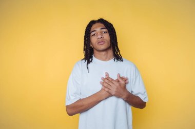 Sarı arka planda beyaz gömlekli örgülü genç bir adam..