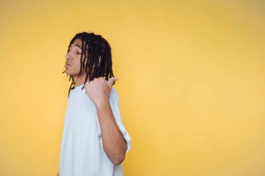 Sarı arka planda beyaz gömlekli, örgülü saçlı biri..