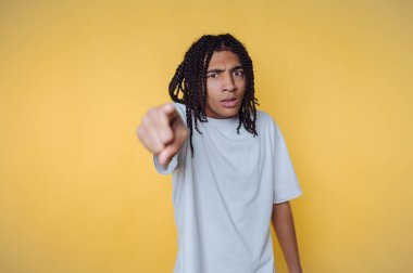 Sarı arka planda ileri bakan rastalı genç adam..