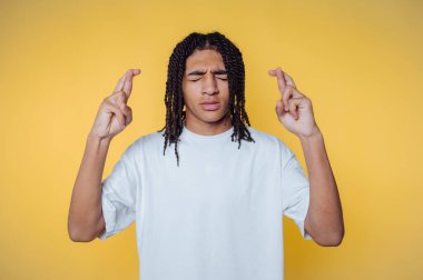 Gözleri kapalı olan kişi sarı arka planda şans diliyor.