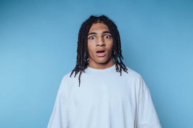 Mavi arka plana şaşırmış genç bir adam..