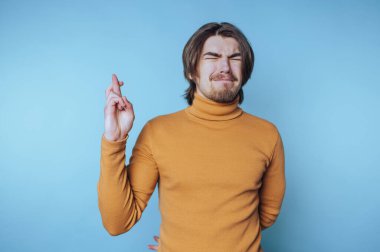 Hardallı balıkçı yakalı bir adam mavi arka planda şans diliyor.