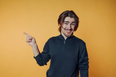 Turuncu arka planda uzun saçlı, gülümseyen adam..