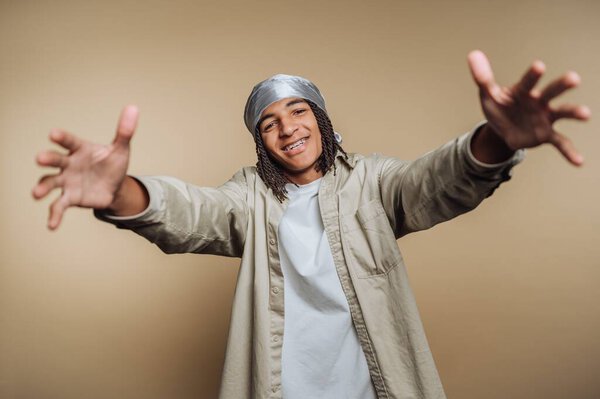 Young man with outstretched arms, smiling, wearing a headscarf.