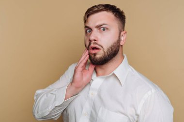 Yüzünü bej arka planda tutan, şaşırmış bir ifadeyle genç bir adamın portresi.