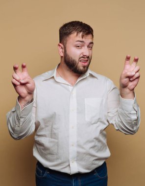 Genç oyuncunun portresi parmaklarıyla tırnak işaretleri yaratıyor, bej arka planda sırıtıyor.