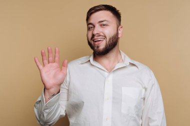 Genç ve mutlu bir adamın portresi büyük bir gülümsemeyle selamlaşır. Bej arka planda sıcaklık ve dostluk yayar.