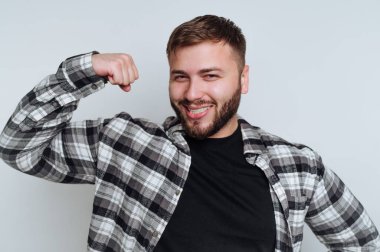 Genç adamın portresi gururla sırıtarak kaslarını esnetir. Beyaz arka planda kendine güven ve güç gösterir.