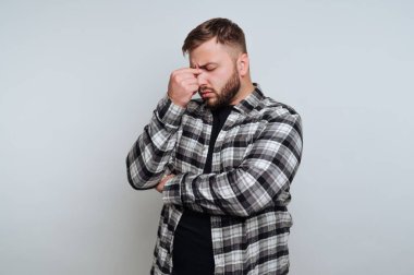 Düşünceli genç bir adamın portresi beyaz arka planda eli alnında sessizce duruyor.