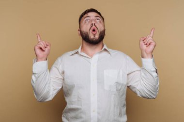 Genç adamın portresi, bej arka planda şaşkınlık ve coşkuyu ifade eden açık bir ağızla yukarıya doğru işaret ediyor.