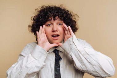 Kıvırcık saçlı, beyaz gömlekli ve kravatlı biri..