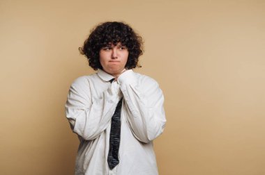 Büyük beden gömlek ve kravatlı kıvırcık saçlı, dalgın görünen biri..