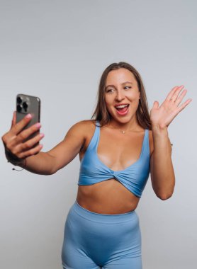 Mavi etekli kadın selfie çekip el sallıyor..