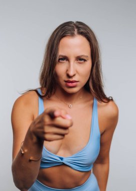 Mavi spor kıyafetli kadın kameraya ciddi bir ifadeyle bakıyor..